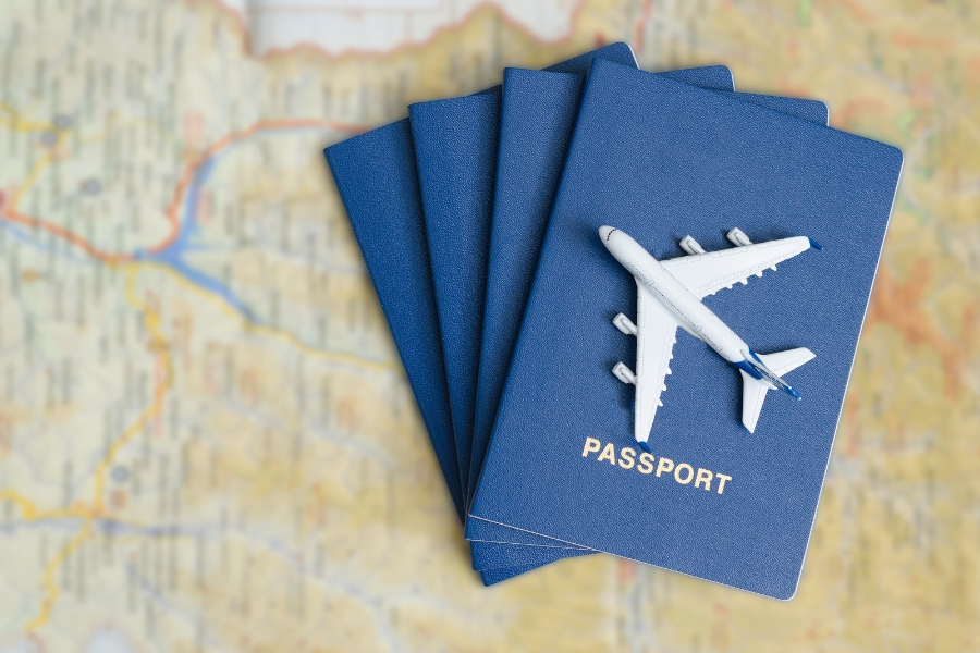 ערימה של דרכונים על גבי מפה. על הדרכון העליון מונח מטוס צעצוע.